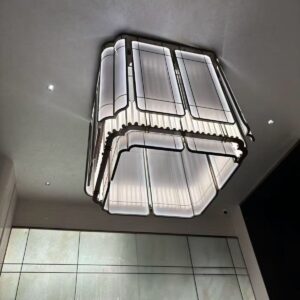 Celestia Frame chandelier installed in modern double height interior Contemporary geometric chandelier with soft ambient lighting Modern architectural ceiling chandelier with framed design Luxury rectangular chandelier for foyer installation Designer LED chandelier with structured metal frame Minimal modern chandelier illuminating luxury interior space